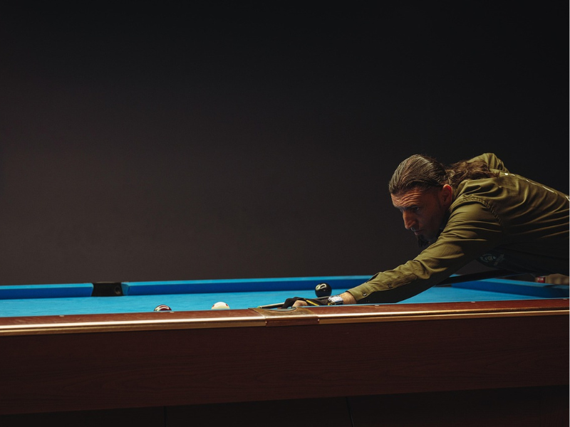 A man shooting the brown ball with the cue ball in american pool