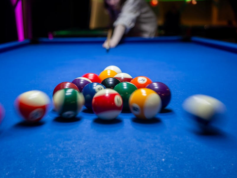 An in motion shot of the cue ball striking a triangle of billiard balls