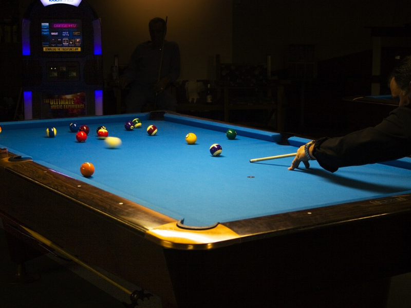 A full table of pool with a man preparing to take a shot