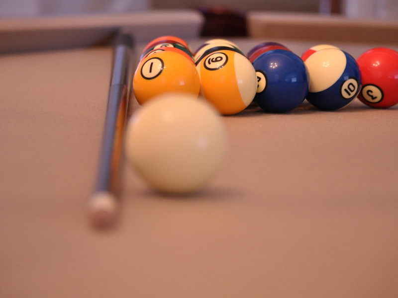 American pool balls with a pool cue resting on table