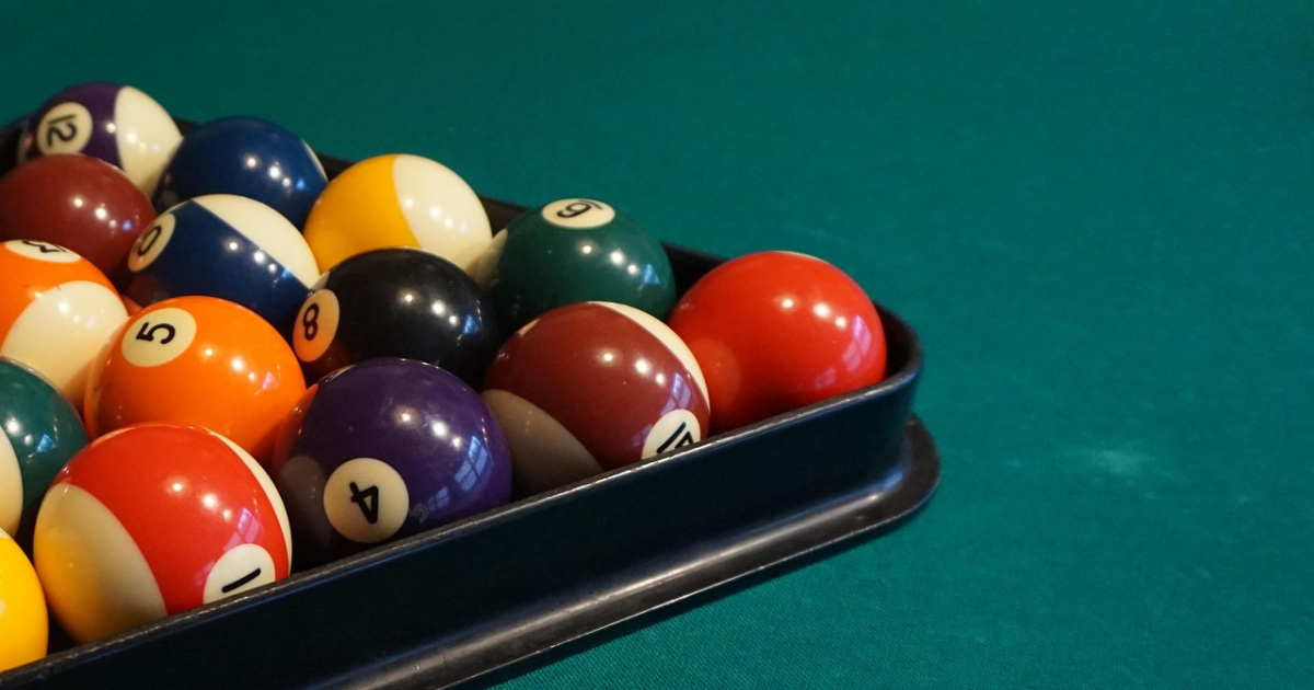 Open pool instructional book beside a cue ball