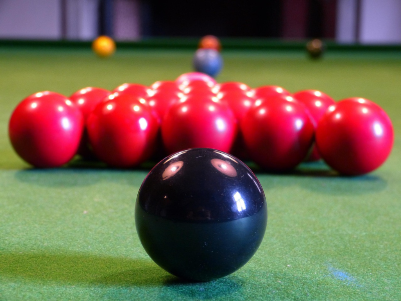 A black ball in front of clustered red snooker balls
