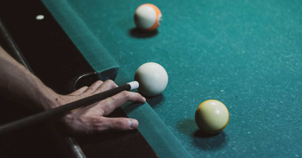 A black pool cue about to strike the cue ball